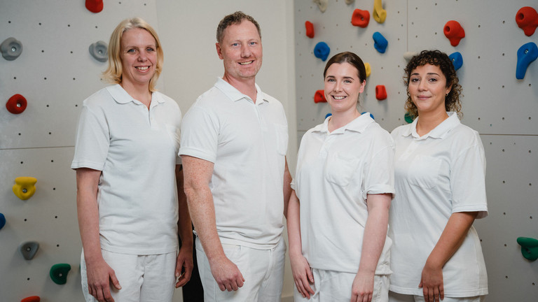 Vier Therapeuten des interdisziplinären Therapiezentrums des Albertinen Krankenhauses vor einer Kletterwand