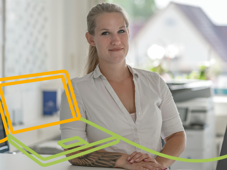Mitarbeiterin der Verwaltung steht an einem Arbeitsplatz mit Laptop und lächelt in die Kamera. Das Bild steht für Organisation, Verwaltung und moderne Büroarbeit. Mitarbeiterin der Verwaltung steht an einem Arbeitsplatz mit Laptop und lächelt in die Kamera. Das Bild steht für Organisation, Verwaltung und moderne Büroarbeit.
