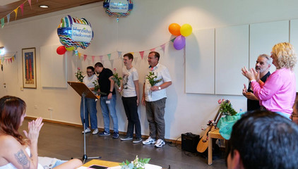 Vier Pflegefachkräfte stehen mit Rosen in den Händen in einem bunt geschmückten Veranstaltungsraum bei der Übergabe ihrer Anerkennungsurkunden bei der Anerkennungsfeier für internationale Pflegefachkräfte im Albertinen Krankenhaus in Hamburg.