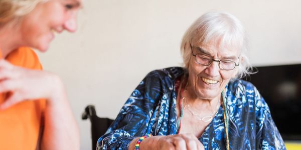 Eine Seniorin und eine Pflegekraft lachen gemeinsam