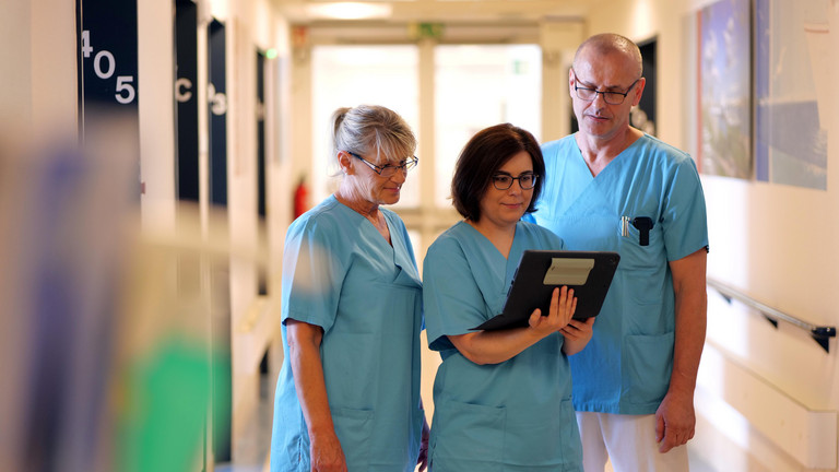 Drei Pflegekräfte besprechen sich auf dem Stationsgang der Inneren Medizin im Albertinen Krankenhaus in Hamburg-Schnelsen