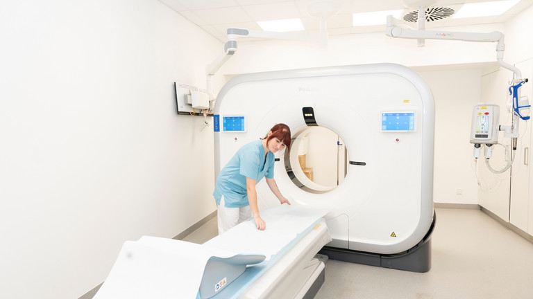 Eine Medizinische Technologin (MTR) in Funktionskleidung bereitet vor einem großen Röntgensystem in einem Untersuchungsraum der Immanuel Klinik Rüdersdorf die Untersuchungsliege vor.