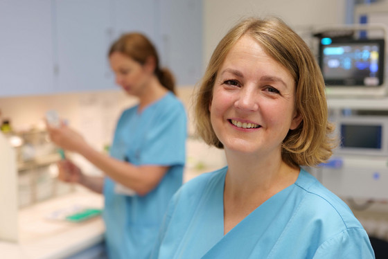 Eine Pflegekraft lächelt im Stationszimmer der Endoskopie und Sonographie in eine Kamera im Albertinen Krankenhaus in Hamburg-Schnelsen