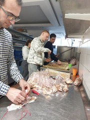 Drei Auszubildende stehen um einem langen Küchentresen und verpacken fertige Plätzchen in Tüten in der Küche der Gemeinde der Baptisten in Berlin-Schönberg beim 4. Azubitag der Auszubildenden von Werkstück Berlin mit Unterstützung von Immanuel Dienstleistungen