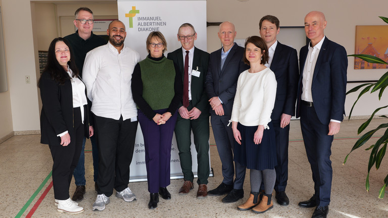 Gruppenfoto mit Karin Schulz, Leiterin der Wohn-Pflegeeinrichtung im Albertinen Haus, Marcus Esch, Pflegedienstleiter, Kevin Lindén, Stellvertretende Pflegedienstleitung, Projektkoordinator, Sozialsenatorin Melanie Schlotzhauer, Albertinen Haus-Geschäftsführer Ralf Zastrau, Staatsrat Tim Angerer, Dr. Elzbieta Kuzma, Projektleiterin, Dr. Thorsten Minuth, Konzerngeschäftsführer der Immanuel Albertinen Diakonie, Thomas Bott, Regionaldirektor AOK Rehinland / Hamburg (von links) zum Präventionspflegeprojekt „SGB Reha“ vor einem Banner im Albertinen Haus in Hamburg