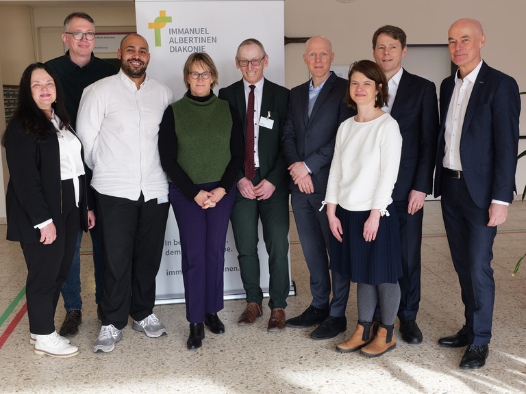 Gruppenfoto mit Karin Schulz, Leiterin der Wohn-Pflegeeinrichtung im Albertinen Haus, Marcus Esch, Pflegedienstleiter, Kevin Lindén, Stellvertretende Pflegedienstleitung, Projektkoordinator, Sozialsenatorin Melanie Schlotzhauer, Albertinen Haus-Geschäftsführer Ralf Zastrau, Staatsrat Tim Angerer, Dr. Elzbieta Kuzma, Projektleiterin, Dr. Thorsten Minuth, Konzerngeschäftsführer der Immanuel Albertinen Diakonie, Thomas Bott, Regionaldirektor AOK Rehinland / Hamburg (von links) zum Präventionspflegeprojekt „SGB Reha“ vor einem Banner im Albertinen Haus in Hamburg