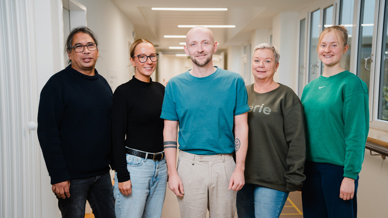 Fünf Personen aus dem Team der Klinik für Psychiatrie und Psychotherapie im Albertinen Krankenhaus in Hamburg stehen nebeneinander in einem Stationsflur und blicken lächelnd in die Kamera. Fünf Personen aus dem Team der Klinik für Psychiatrie und Psychotherapie im Albertinen Krankenhaus in Hamburg stehen nebeneinander in einem Stationsflur und blicken lächelnd in die Kamera.