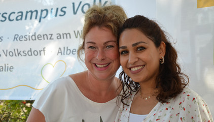 Zwei Mitarbeiterinnen blicken lächelnd in die Kamera bei den Ständen des Gesundheitscampus Volksdorf der Immanuel Albertinen Diakonie beim Stadtteilfest Volksdorf in Hamburg