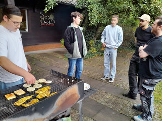 Auszubildende stehen auf einer Terrasse an einem Grill