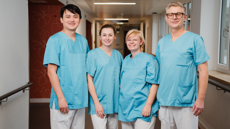 Vier Pflegekräfte in blauen Kasacks auf einem Stationsflur des Albertinen Zentrums für Altersmedizin in Hamburg Schnelsen