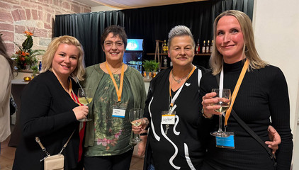 Vier Mitarbeiterinnen mit Wein- und Getränkegläsern in der Hand blicken in die Kamera beim Zusammenschluss von Diakonie Werratal und Immanuel Diakonie Südthüringen im Kressehof im Meininger Ortsteil Walldorf