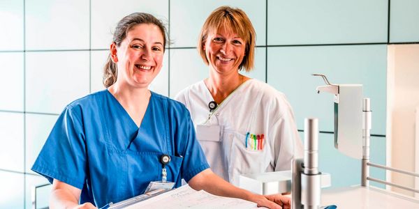 Zwei Pflegekräfte lächeln und freuen sich auf neue Kolleginnen und Kollegen