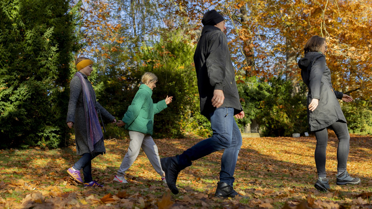 Eine Familie mit zwei Kindern beim Spaziergang durch den herbstlich belaubten Wald Eine Familie mit zwei Kindern beim Spaziergang durch den herbstlich belaubten Wald