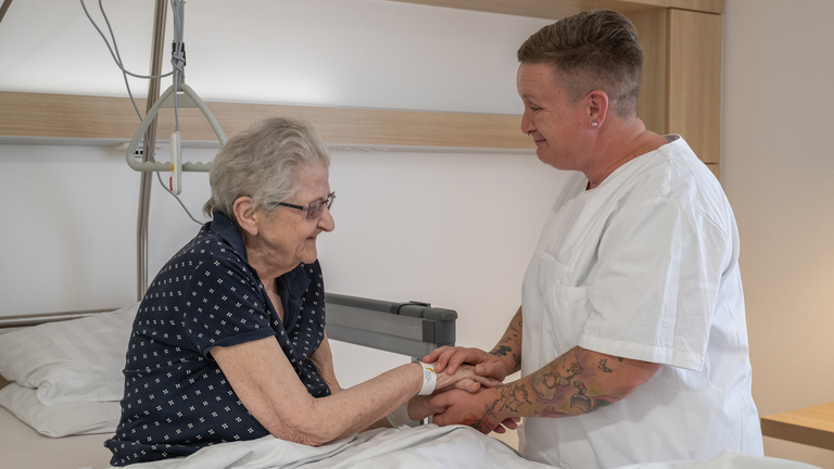 Pflegeassistenz hält Hand von Patientin - Pflege  - Immanuel Klinikum Bernau