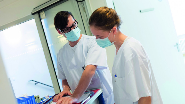 Zwei Pflegekräfte stehen beratend an einem Tisch, Ausbildung in der Pflege, Albertinen Krankenhaus, Hamburg-Schnelsen
