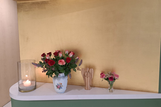 Eine brennende Kerze und Blumen für einen verstorbenen Gast