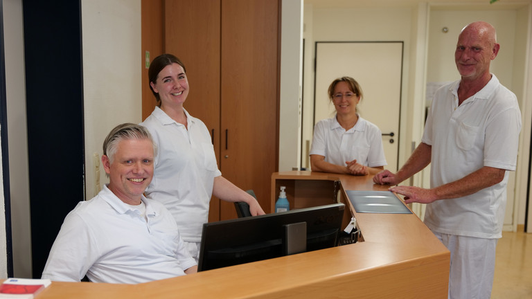 Mehrere Therapeutinnen und Therapeuten in weißer Funktionskleidung stehen am Empfangstresen bei Physikofit für Physiotherapie im Interdisziplinären Therapiezentrum im Albertinen Krankenhaus in Hamburg und blicken in die Kamera Mehrere Therapeutinnen und Therapeuten in weißer Funktionskleidung stehen am Empfangstresen bei Physikofit für Physiotherapie im Interdisziplinären Therapiezentrum im Albertinen Krankenhaus in Hamburg und blicken in die Kamera