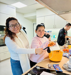 Zwei Pflegekräfte rühren Kuchenteig in einer Schüssel an, auf der Arbeitsfläche liegen Backzutaten