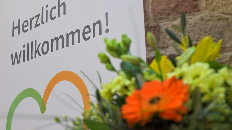 Blumenstrauß vor einem Plakat mit der Aufschrift "Herzlich willkommen" beim Zusammenschluss von Diakonie Werratal und Immanuel Diakonie Südthüringen im Meininger Ortsteil Walldorf