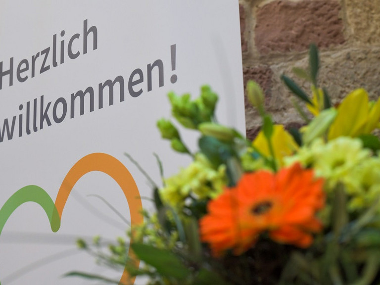 Blumenstrauß vor einem Plakat mit der Aufschrift "Herzlich willkommen" beim Zusammenschluss von Diakonie Werratal und Immanuel Diakonie Südthüringen im Meininger Ortsteil Walldorf
