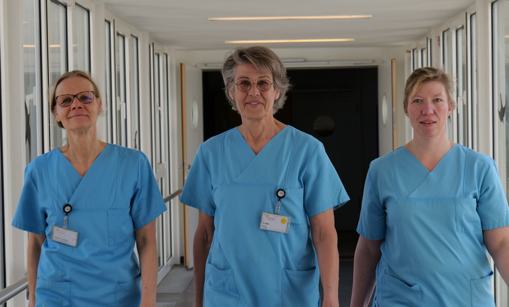 Stefanie Heldt, Leitung therapeutische Dienste, Geriatrie und Physikalische Medizin im Evangelischen Amalie Sieveking Krankenhaus, läuft in blauer Funktionskleidung mit zwei Kolleginnen durch einen Verbindungsgang im Evangelischen Amalie Sieveking Krankenhaus in Hamburg.