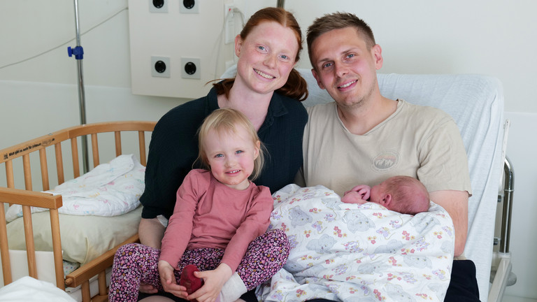 Ingrid und Sebastian P. aus Elmshorn mit Tochter Ylvi und ihrem neugeborenen Sohn Momme sitzen gemeinsam auf dem Bett in einem Zimmer im Albertinen Geburtszentrum des Albertinen Krankenhauses in Hamburg-Schnelsen.