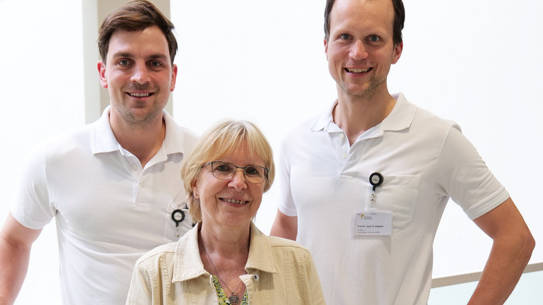 Assistenzarzt Dr. Julian Dittmann, Patientin Anja P. und Chefarzt der Klinik für Gynäkologie und Geburtshilfe Prof. Dr. Rüdiger Klapdor blicken in der Eingangshalle des Albertinen Krankenhauses in Hamburg lächelnd in die Kamera