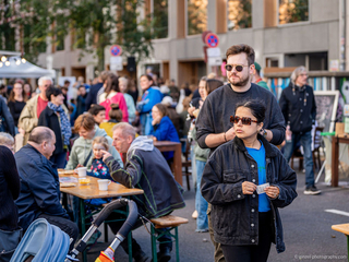 Besucher und Besucherinnen sitzen an Tischen und laufen durch die Straße, 6. Zelterstraßenfest, feiern für den guten Zweck, Beratung plus Leben, Soziale Einrichtung, Berlin